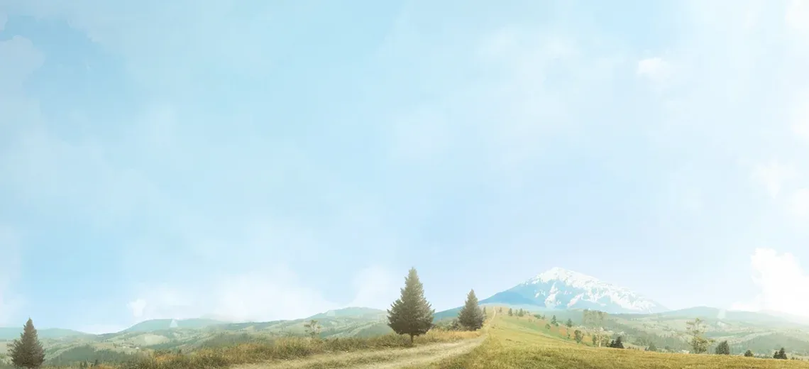 Open green hills and mountains beneath a soft blue sky.