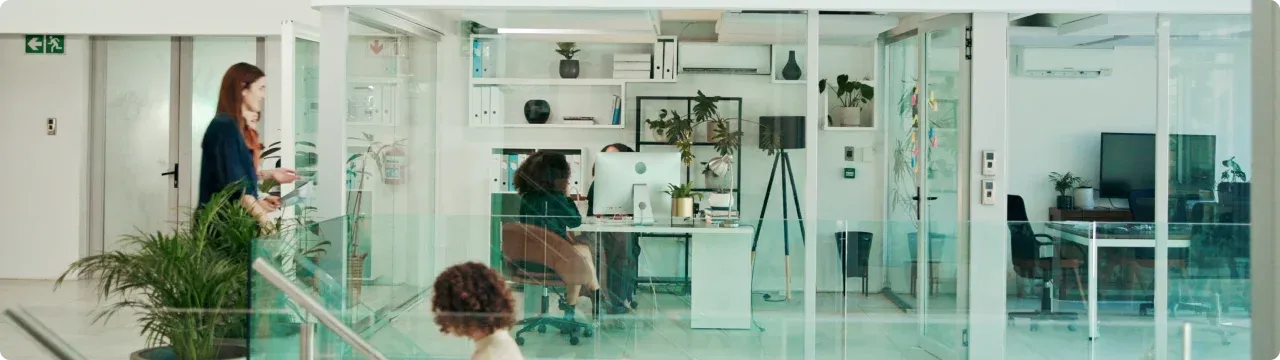 People working inside a modern glass office.