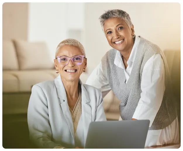 Two colleagues smiling beside a laptop while discussing employee support.